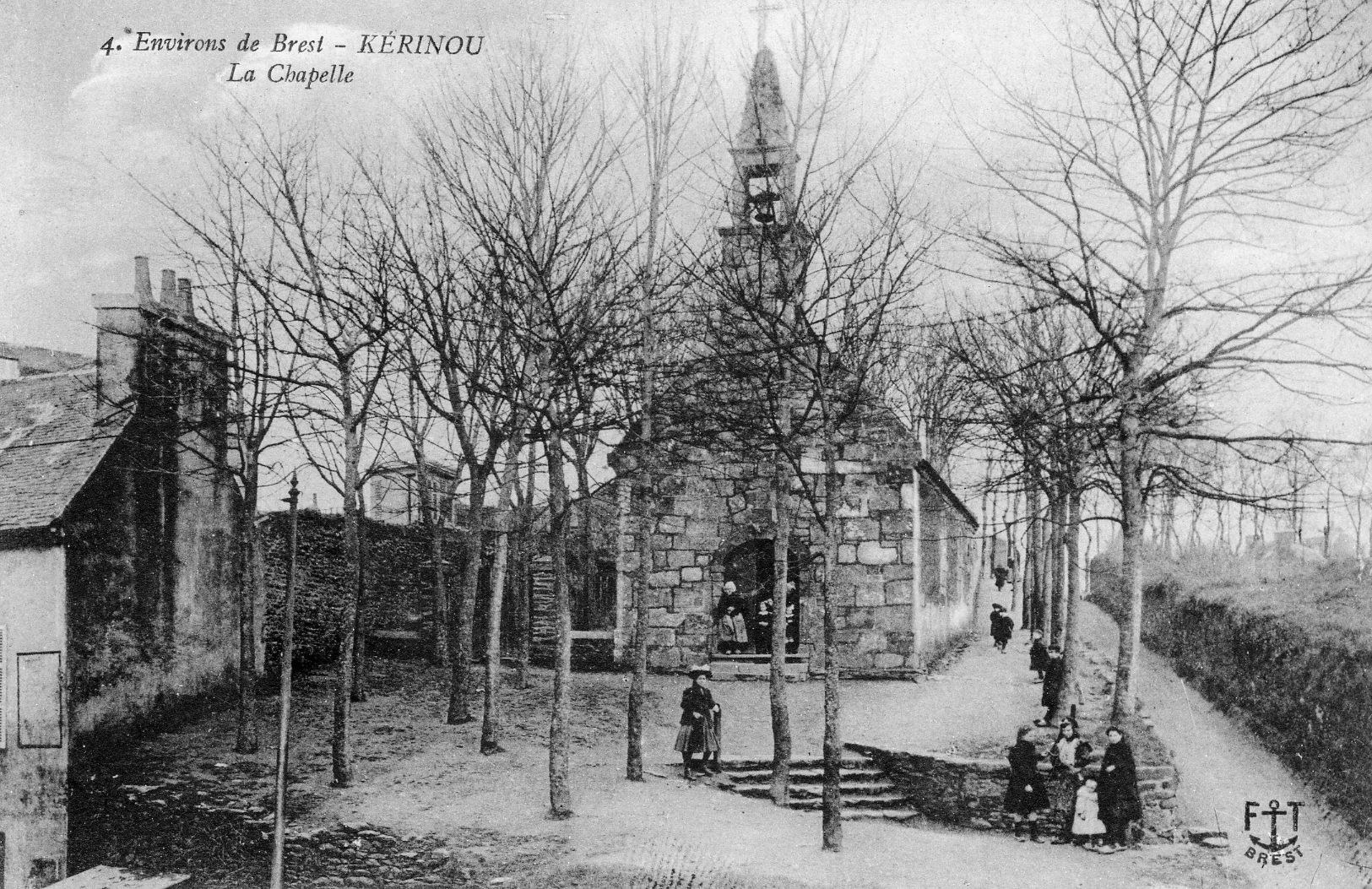 Carte postale ancienne en noir et blanc : une petite chapelle de pierre à clocheton, au bout d'une allée d'arbres dénudés, quelques enfants et une femme en coiffe sur les marches