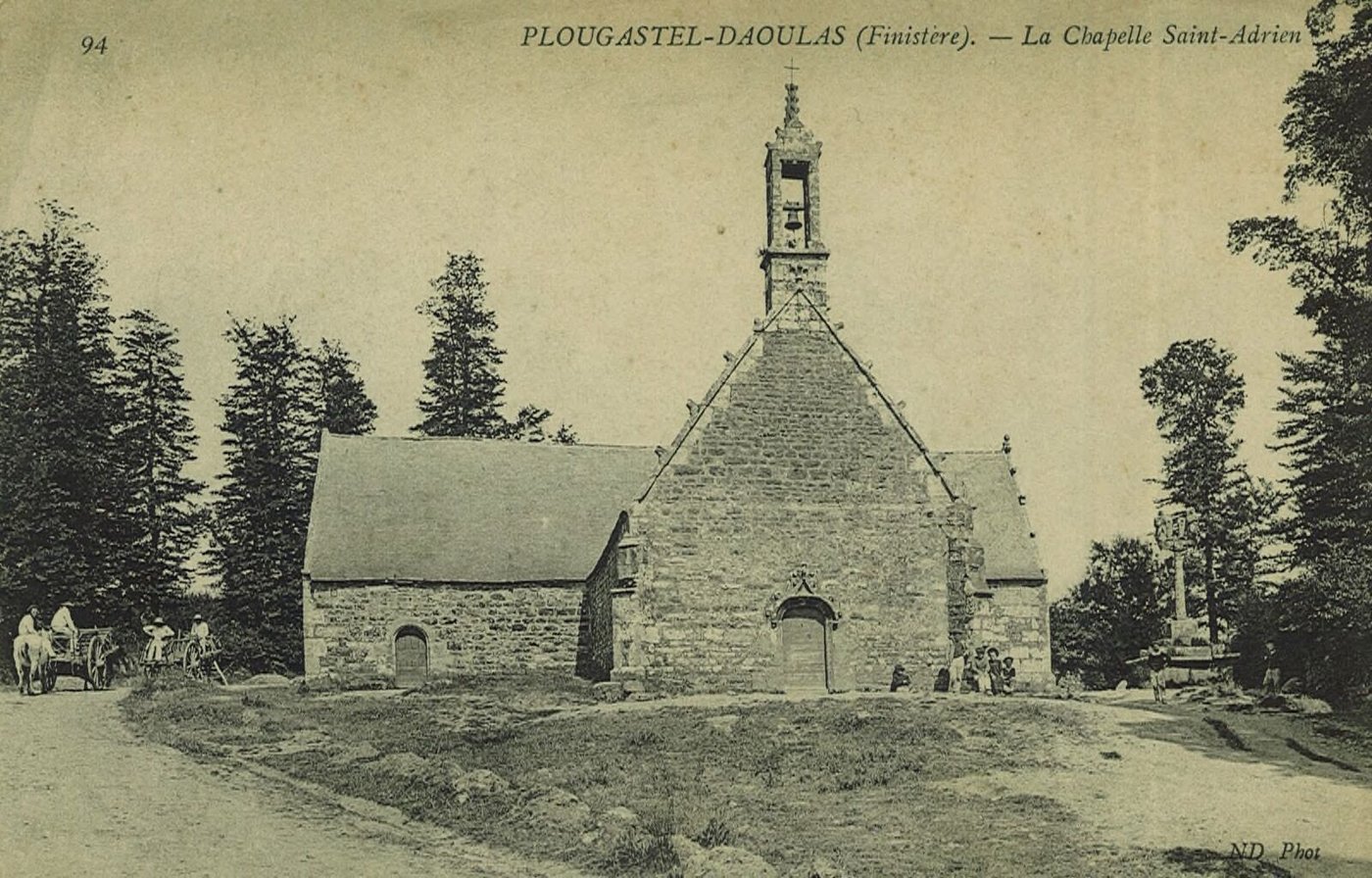 Carte postale ancienne : une petite chapelle de granit avec un clocher à jour, un calvaire, des arbres et une charrette